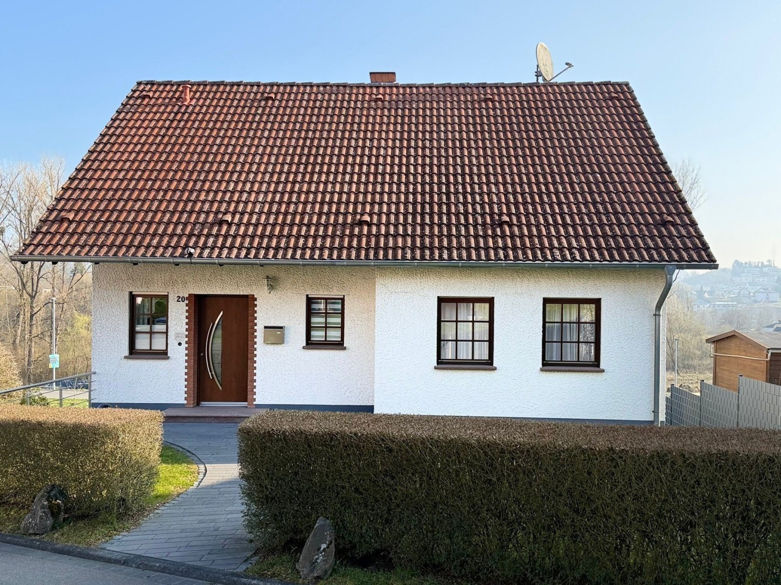 Satteldach eines Einfamilienhauses vor der Bearbeitung: verwitterte, stellenweise veralgte rotbraune Dachziegel.