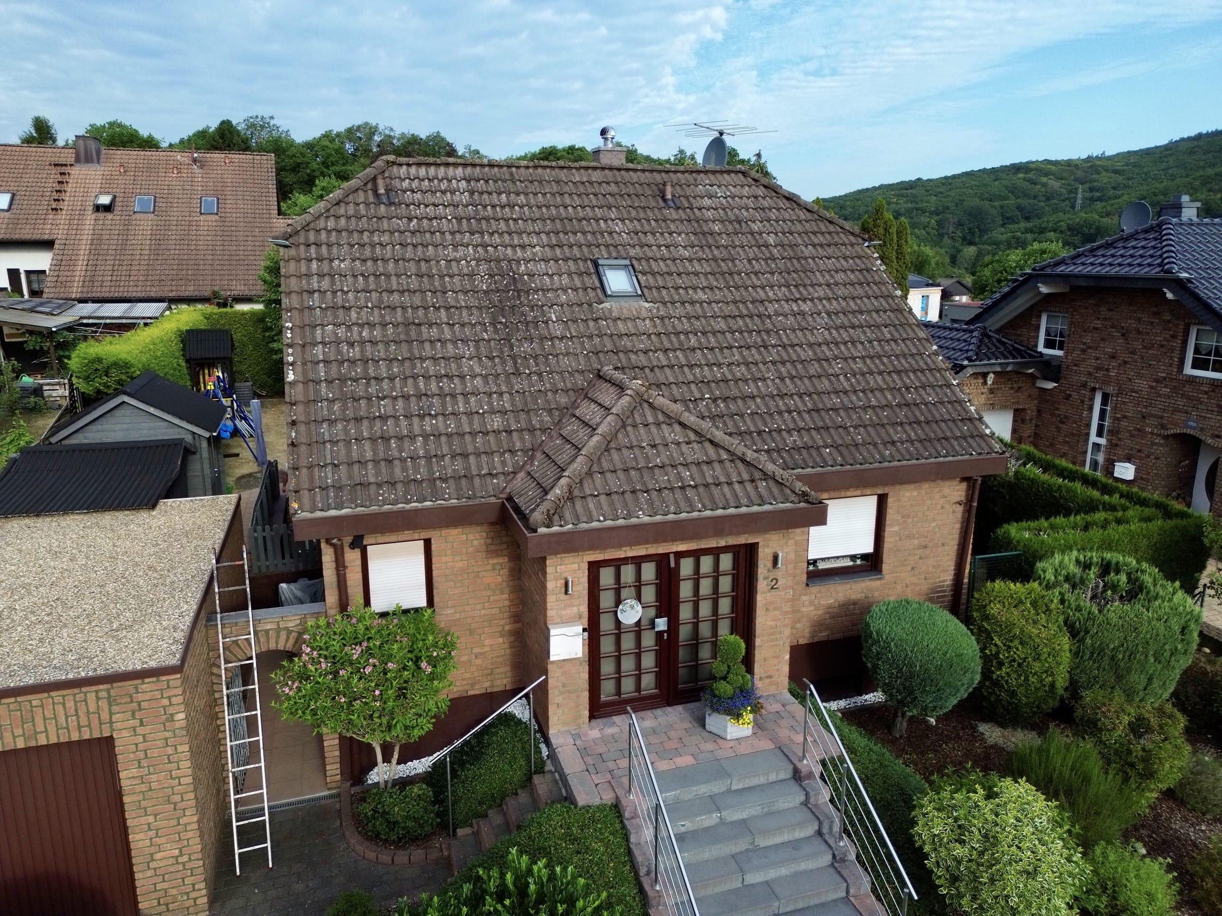 Walmdach eines Klinkerhauses vor der Bearbeitung: verwitterte, fleckige braune Dachziegel.